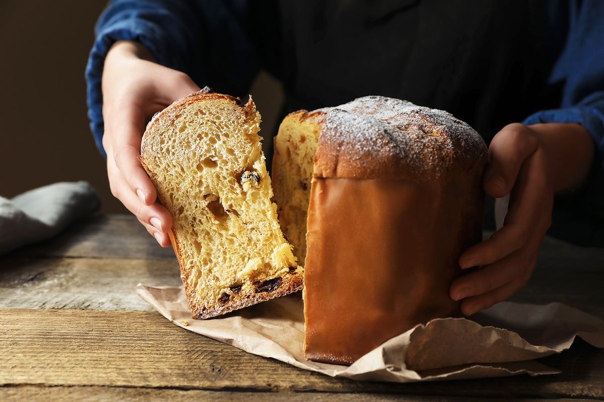Woman,Taking,Slice,Of,Delicious,Panettone,Cake,With,Powdered,Sugar