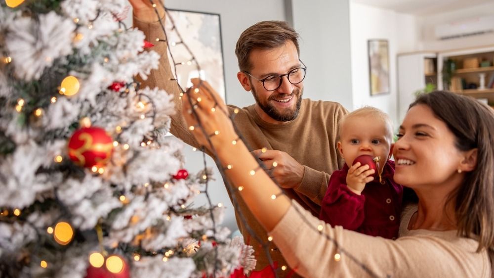 Young,Parents,Having,Fun,Decorating,Christmas,Tree,With,Their,Cute