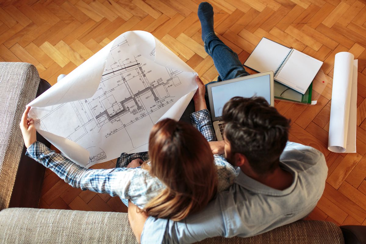 Young,Couple,Examining,Blueprints,Of,They,New,House.moving,House,Concept.Young couple examining blueprints of they new house.Moving house concept. CSOK