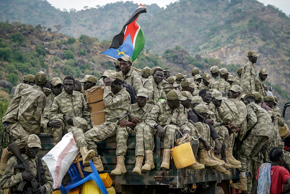 Soldiers belonging to the South Sudanese Unified Forces sit on a track as they depart after a deployment ceremony at the Luri Military Training Centre in Juba on November 15, 2023. Hundreds of former rebels and government troops in South Sudan's Unified Forces were deployed at a long-overdue ceremony on November 15, 2023, marking progress for the country's lumbering peace process. (Photo by Peter Louis GUME / AFP) konfliktus