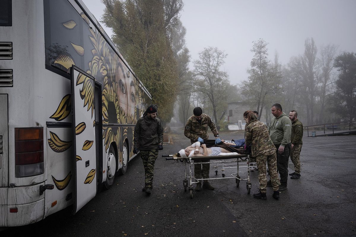 DONETSK OBLAST, UKRAINE - OCTOBER 26: Members of 'Hospitallers', one of Ukraine's volunteer medical teams, carry an injured Ukrainian soldier from a hospital close to the front with a stretcher to for treatment in a bus converted into an ambulance in Donetsk Oblast, Ukraine on October 26, 2023. Volunteer medical teams take Ukrainian soldiers injured in the ongoing conflicts between Russia and Ukraine away from areas near the front lines and transport them to hospitals in the country's metropolitan cities by private vehicles.  Paramedics pick up seriously injured soldiers at the frontline with a bed bus converted into an ambulance and transport them to hospitals in major cities of Ukraine, providing medical support to the soldiers during the bus journey. Ozge Elif Kizil / Anadolu (Photo by Ozge Elif Kizil / ANADOLU / Anadolu via AFP)