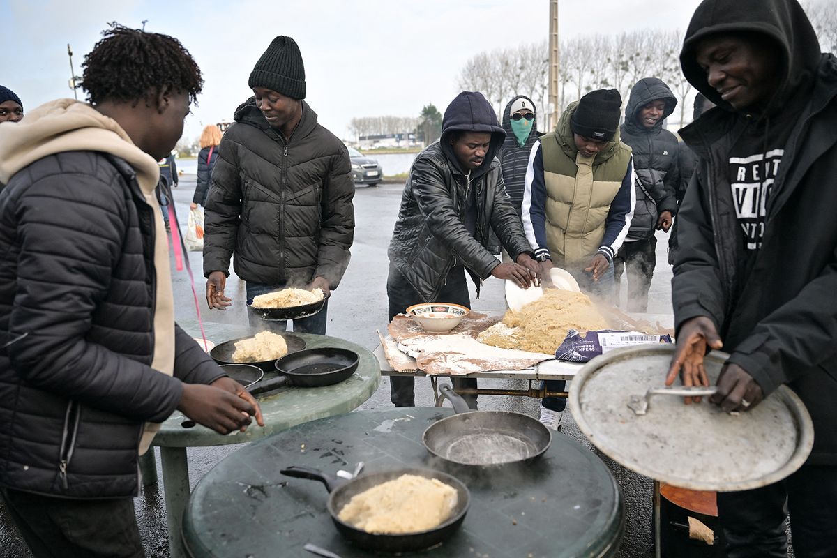 Sudanese migrants prepares a typical Sudanese meal with tuna, water and flour provided by charity associations, in a migrant camp, in Ouistreham, northwestern France on December 11, 2023. Following a recent justice decision on this migrant camp, mayor of Ouistreham has to bring water and staff to this camp within this week, otherwise there will be sanctions, in Ouistreham, on December 11, 2023. (Photo by LOU BENOIST / AFP)
