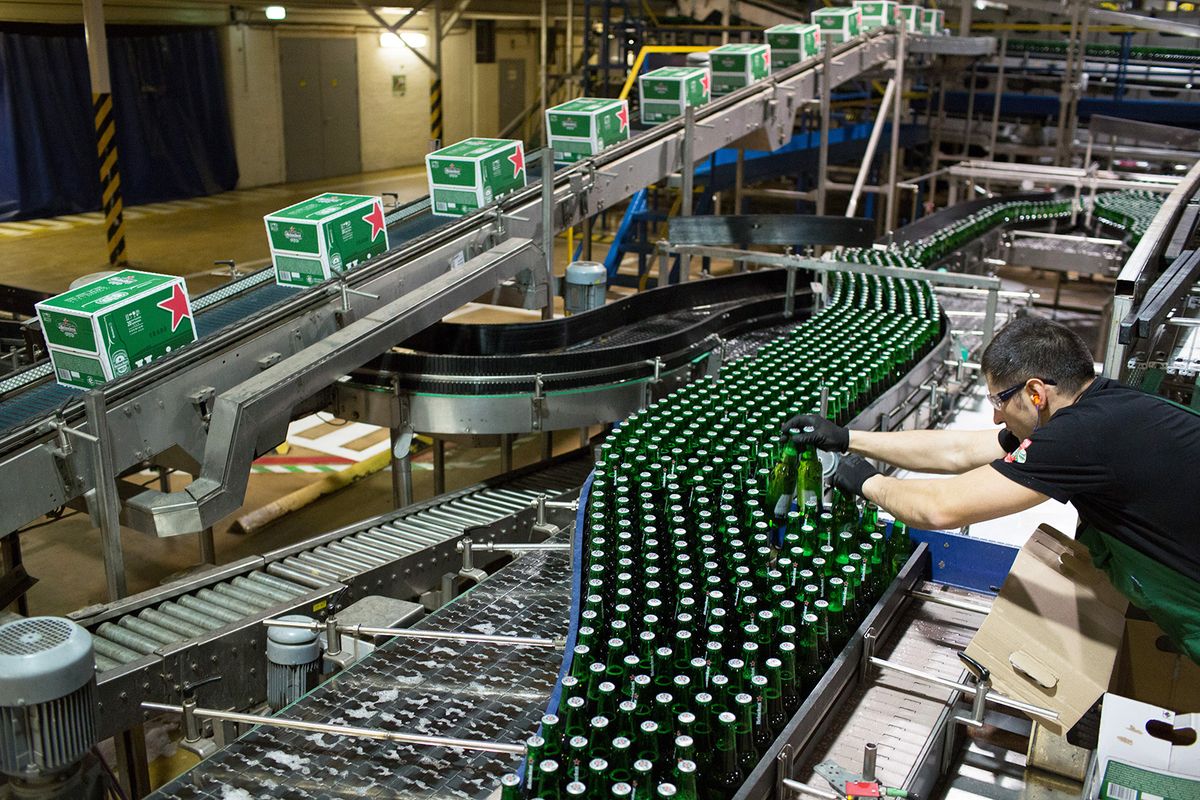 An employee lifts bottles of Heineken beer from the production line at the Heineken NV brewery in Saint Petersburg, Russia, on Wednesday, Nov. 18, 2015. Heineken reported estimate-beating sales growth boosted by a warm European summer as the world's third-largest brewer prepares to become a distant number two. Photographer: Andrey Rudakov/Bloomberg via Getty Images