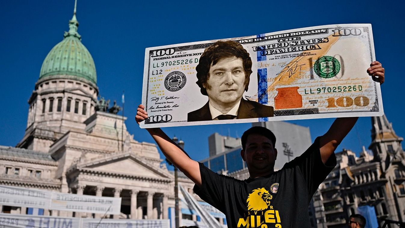 A supporter of Argentina's President-elect Javier Milei displays a one hundred dollar bill placard with an image of the future president as he waits outside the Congress before his inauguration ceremony, in Buenos Aires on December 10, 2023. Javier Milei will on Sunday be sworn in as Argentina's president, as the country steels itself for harsh spending cuts and economic reforms aimed at curbing rampant inflation. (Photo by Luis ROBAYO / AFP)