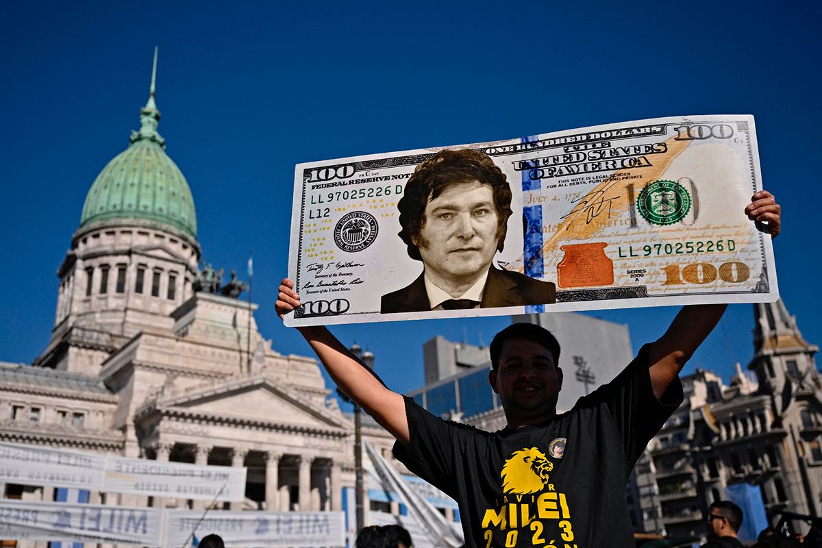 A supporter of Argentina's President-elect Javier Milei displays a one hundred dollar bill placard with an image of the future president as he waits outside the Congress before his inauguration ceremony, in Buenos Aires on December 10, 2023. Javier Milei will on Sunday be sworn in as Argentina's president, as the country steels itself for harsh spending cuts and economic reforms aimed at curbing rampant inflation. (Photo by Luis ROBAYO / AFP)