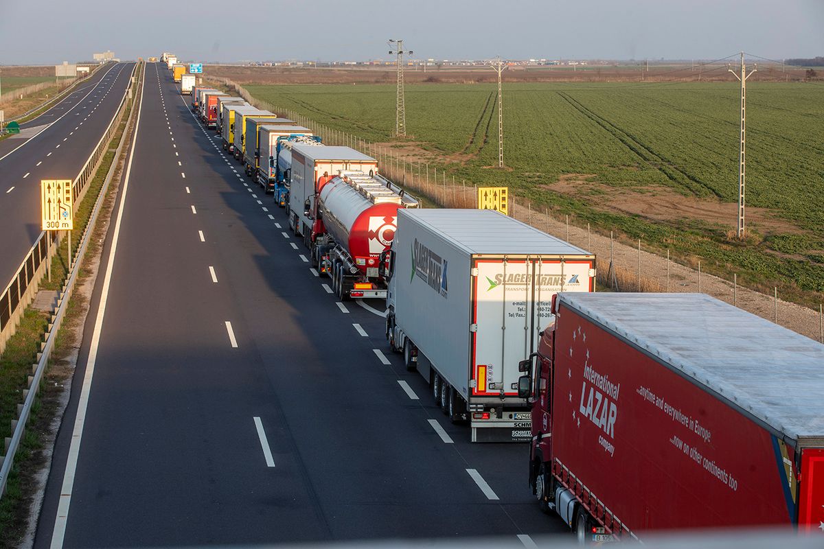 Csanádpalota, 2020. március 20.
Kamionok várakoznak a csanádpalotai magyar-román autópálya-határátkelőhely közelében, az M43-as autópályán 2020. március 20-án. Ezen a napon tizenkét órásra nőtt a kamionok várakozási ideje, a várakozásra kényszerülő árufuvarozóknak a rendőrök és a katasztrófavédelem munkatársai vizet osztanak. Több mint 35 kilométeres kamionsor alakult ki a Romániába tartó tehergépjárművekből.
MTI/Rosta TiborCsanádpalota, 2020. március 20.Kamionok várakoznak a csanádpalotai magyar-román autópálya-határátkelőhely közelében, az M43-as autópályán 2020. március 20-án. Ezen a napon tizenkét órásra nőtt a kamionok várakozási ideje, a várakozásra kényszerülő árufuvarozóknak a rendőrök és a katasztrófavédelem munkatársai vizet osztanak. Több mint 35 kilométeres kamionsor alakult ki a Romániába tartó tehergépjárművekből.MTI/Rosta Tibor