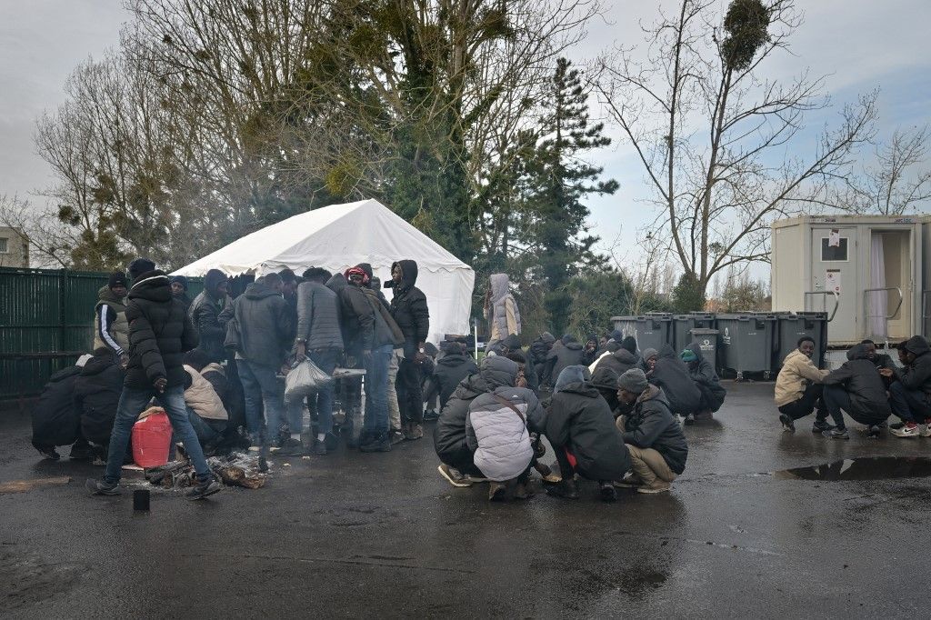 Sudanese migrants have their meal provided by charity associations, in a migrant camp, in Ouistreham, northwestern France on December 11, 2023. Following a recent justice decision on this migrant camp, mayor of Ouistreham has to bring water and staff to this camp within this week, otherwise there will be sanctions, in Ouistreham, on December 11, 2023. (Photo by LOU BENOIST / AFP)