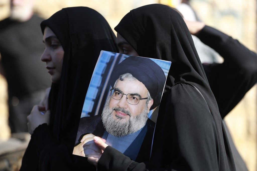 A woman holds a picture of Hezbollah chief Hassan Nasrallah during the funeral of a Hezbollah member who was killed in southern Lebanon in cross-border fire with Israeli troops, during his funeral in a south Beirut suburb, on November 6, 2023. The Lebanon-Israel border has seen regular cross-border shelling over the past month, with firing between the Israeli military on one side and the powerful Hezbollah and its allies on the other. (Photo by AHMAD AL-RUBAYE / AFP)