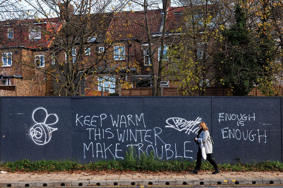 LONDON, UNITED KINGDOM - NOVEMBER 30: A member of the public walks past a graffiti sign that reads 'Keep warm this winter, make trouble' on November 30, 2023 in Harrow, London, United Kingdom. (Photo by Dan Kitwood/Getty Images)