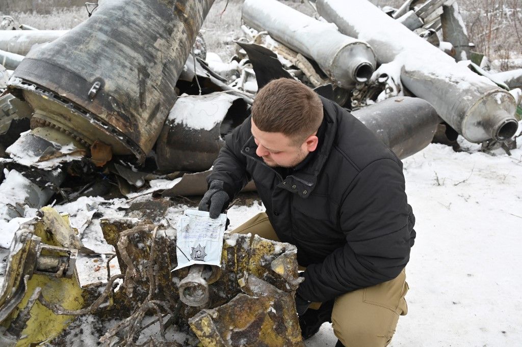 In this photo, taken on January 6, 2024, a prosecutor's office expert inspects remains of a missile used during an attack on Kharkiv on January 2. (Photo by SERGEY BOBOK / AFP)