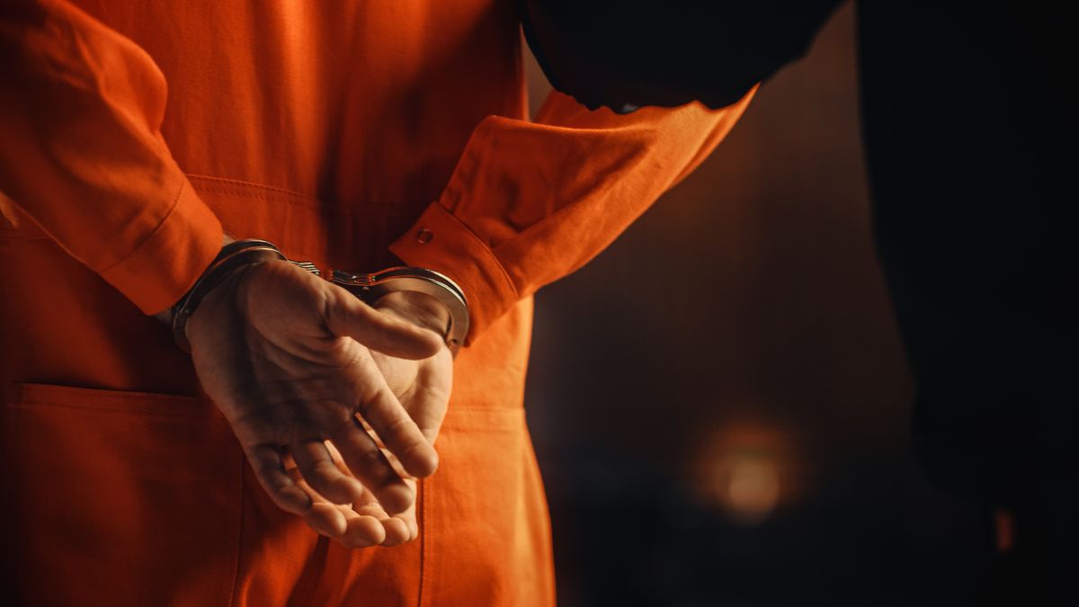 Cinematic Close Up Footage of a Handcuffed Convict at a Law and Justice Court Trial. Handcuffs on Accused Criminal in Orange Jail Jumpsuit. Law Offender Sentenced to Serve Jail Time.