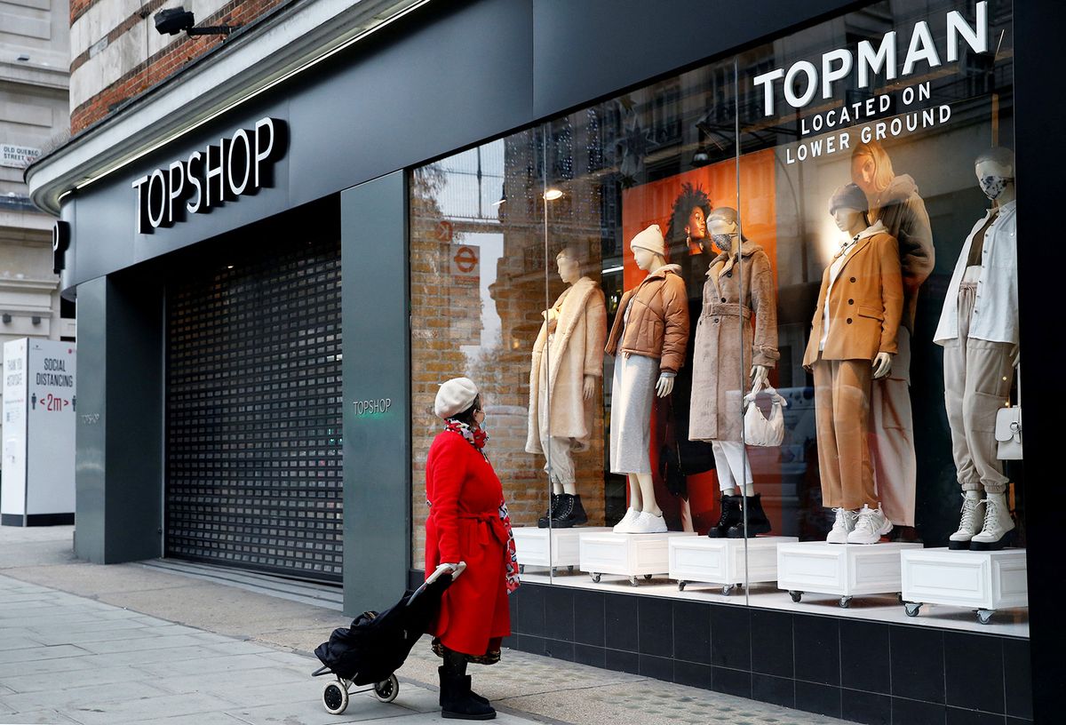 A pedestrian looks in the window of a and closed-down Topman clothes store, operated by Arcadia, in central London on November 30, 2020. British clothing retailer Arcadia, ravaged by coronavirus lockdowns and fierce online competition, remains on the brink of bankruptcy despite an emergency loan offer, the BBC reported Monday. (Photo by Hollie Adams / AFP)