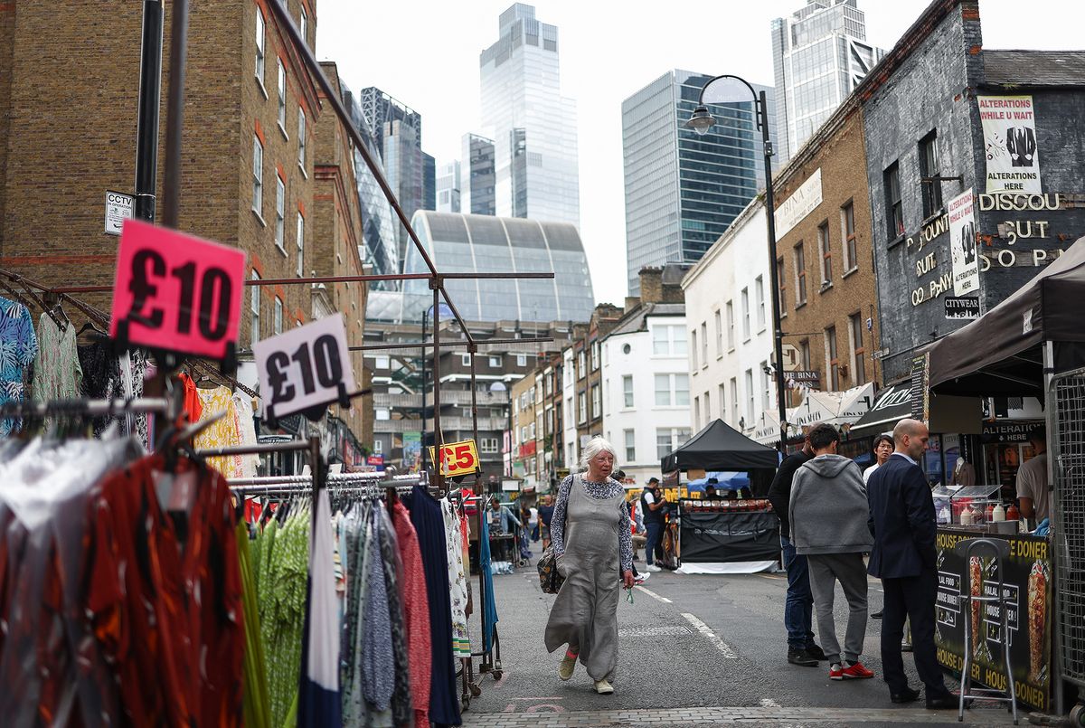 Shoppers browse stalls in Petticoat Lane Market, against the backdrop of The City of London financial district in London on August 11, 2023. Britain's economy expanded slightly over the second quarter thanks to strong output in June and despite inflation remaining high, official data showed Friday (Photo by HENRY NICHOLLS / AFP)