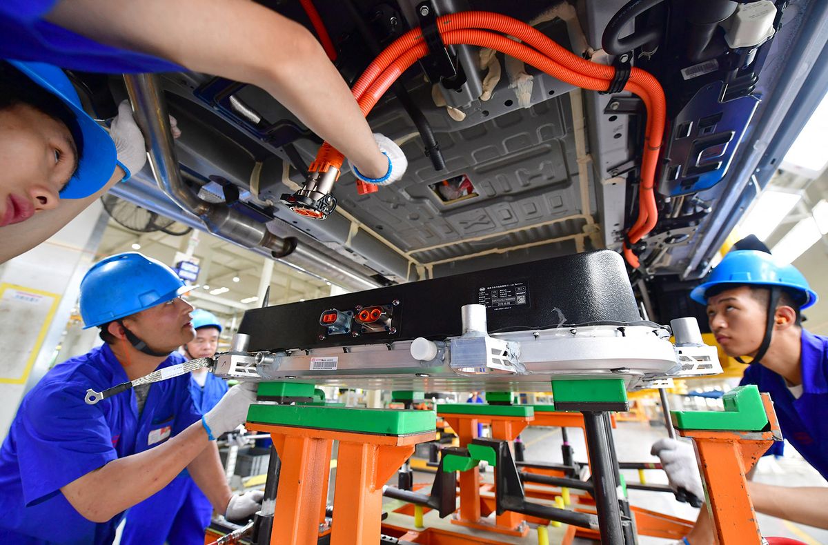 (190613) -- XI'AN, June 13, 2019 (Xinhua) -- Assembly workers install the battery pack for a new energy vehicle at Xi'an plant of BYD Auto in Xi'an, northwest China's Shaanxi Province, June 12, 2019. Sales of new energy vehicles (NEVs) kept growing last month, edging up 1.8 percent year on year, according to the China Passenger Car Association. The government earlier this month announced measures to boost car sales, such as prohibiting local governments from imposing any limit on the consumption and use of NEVs. (Xinhua/Shao Rui) (Photo by XINHUA / Xinhua via AFP)