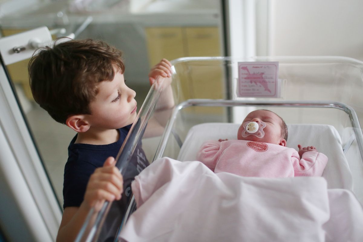 A newborn with her brother at the maternity ward