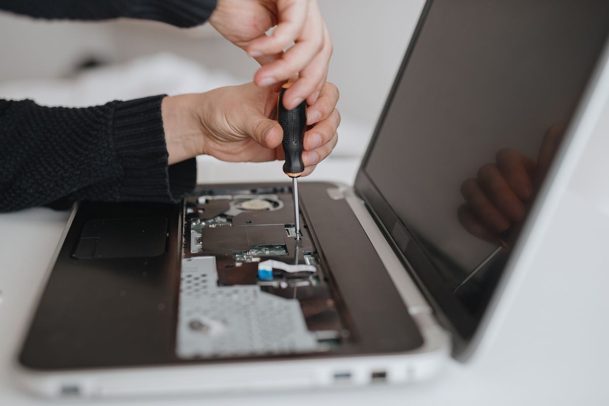 Un hombre desmonta un concepto de servicio y reparación de computadoras portátiles.