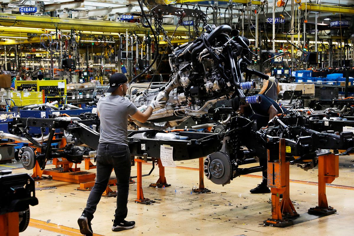 Workers put engines on the frame as Ford Motor Co. fuel powered F-150 trucks under production at their Truck Plant in Dearborn, Michigan on September 20, 2022. Construction crews are back at Dearborn, remaking Ford's century-old industrial complex once again, this time for a post-petroleum era that is finally beginning to feel possible.The manufacturing operation's prime mission in recent times has been to assemble the best-selling F-150, a gasoline-powered vehicle (Photo by JEFF KOWALSKY / AFP)