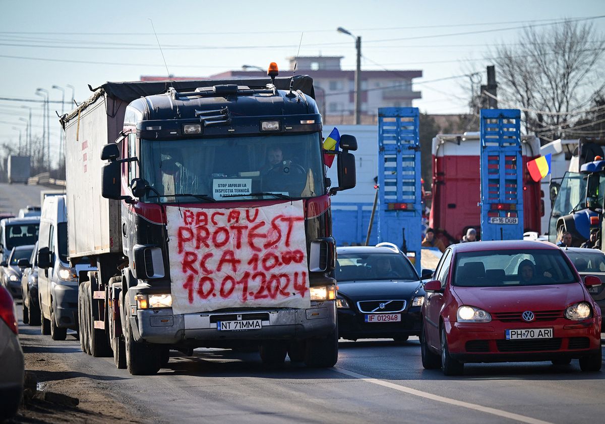ROMANIA-FARMERS-TRANSPORTERS-PROTEST
A Romanian truck driver displays a banner on a truck on the road to Bucharest in Afumati village on January 16, 2024. All over Romania around 4,500 truck drivers and farmers slowed traffic around several cities, including the capital Bucharest, voicing a string of grievances from high tax rates to slow compensation payouts. Past days, protesters also gathered at border areas, temporarily blocking the northeastern border with Ukraine. The truck drivers are complaining over high insurance and tax rates and long waiting times at the borders. At the same time, the farmers are seeking speedier payment of subsidies and compensation for those affected by drought or by disruptions caused by the import of Ukrainian cereals. (Photo by Daniel MIHAILESCU / AFP)