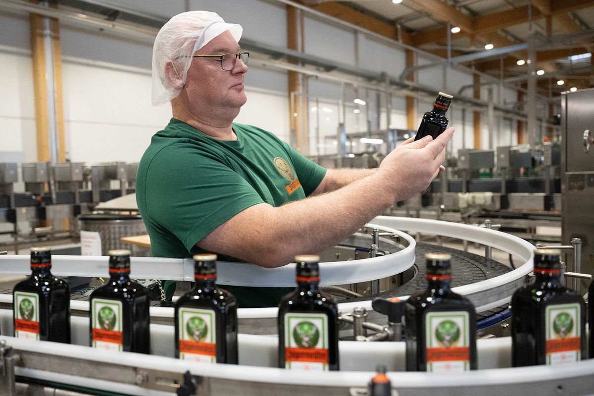 28 November 2023, Saxony, Kamenz: Karsten Höhne, Production Manager, inspects a glass bottle in the Jägermeister herbal liqueur manufacturer's bottling plant. 30 years after the foundation stone was laid in Upper Lusatia, the site is being expanded with a new barrel warehouse. Photo: Sebastian Kahnert/dpa (Photo by Sebastian Kahnert/picture alliance via Getty Images)