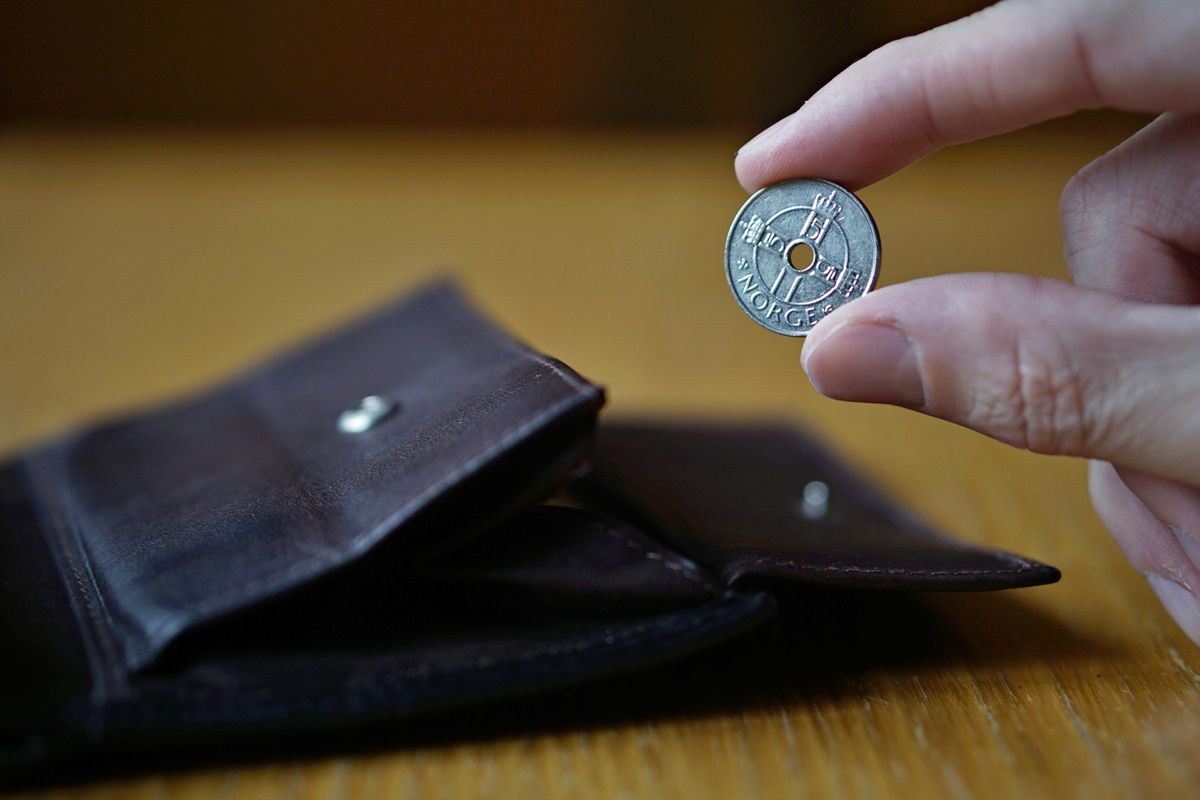 Male hand holding a silver Norwegian coin (Norwegian krone,NOK)