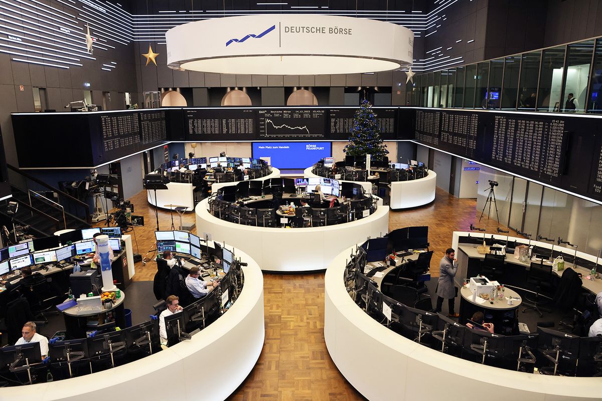 Traders work in front of a chart of Germany's share index DAX that is diplayed (in background) at the stock exchange in Frankfurt am Main, western Germany. German stocks reached a record high on December 14, 2023, buoyed by the US Federal Reserve decision to leave its key lending rate at a 22-year-high. (Photo by Daniel ROLAND / AFP)