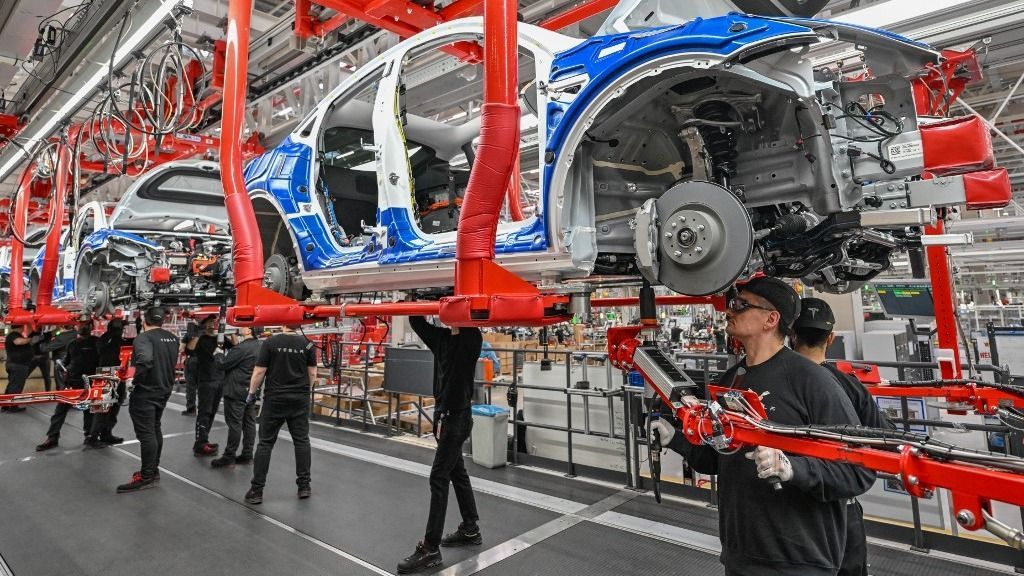 One year Tesla Gigafactory Berlin Brandenburg20 March 2023, Brandenburg, Grünheide: Employees of the Tesla Gigafactory Berlin Brandenburg work on a production line of a Model Y electric vehicle. The Tesla plant was opened and put into operation on March 22, 2022. In the meantime, about 10,000 people are employed there. (to dpa "One year of Tesla plant in Germany - showcase factory and object of dispute") Photo: Patrick Pleul/dpa (Photo by PATRICK PLEUL / DPA / dpa Picture-Alliance via AFP) üzleti hangulat