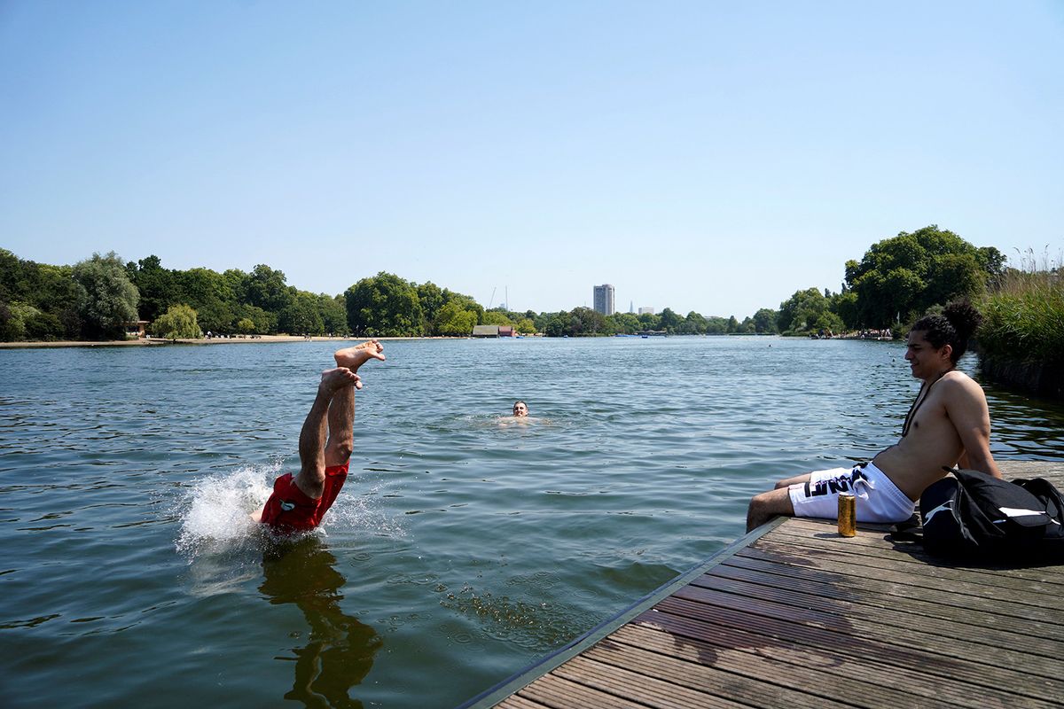 A man jumps into the Serpentine lake to cool off in Hyde Park, west London, on July 19, 2022 as the country experiences an extreme heat wave. Britain could hit 40 Celsius (104 Fahrenheit) for the first time, forecasters said, causing havoc in a country unprepared for the onslaught of extreme heat that authorities said was putting lives at risk. (Photo by Niklas HALLE'N / AFP)