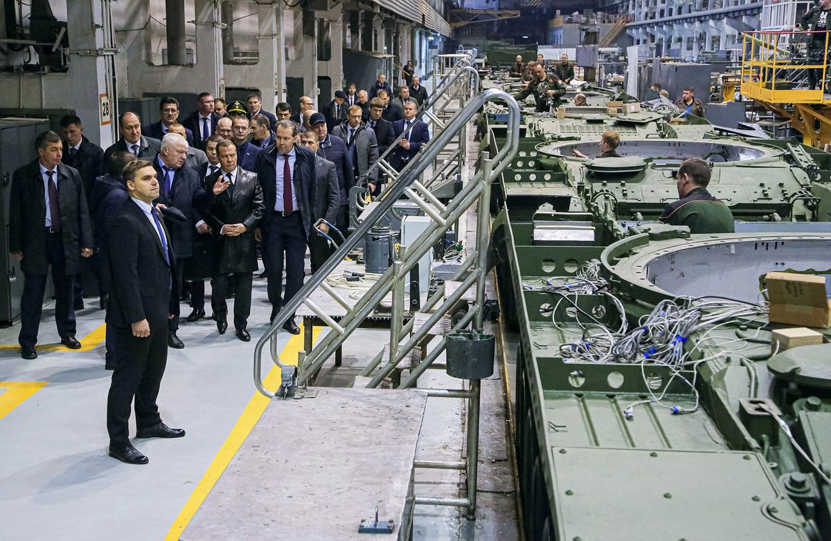 Russia's former leader Dmitry Medvedev (wearing a leather coat), a President Putin ally who is now deputy chairman of the country's security council, tours Uralvagonzavod, Russia's main tank factory in the Urals, in Nizhny Tagil on October 24, 2022. (Photo by SPUTNIK / AFP)
