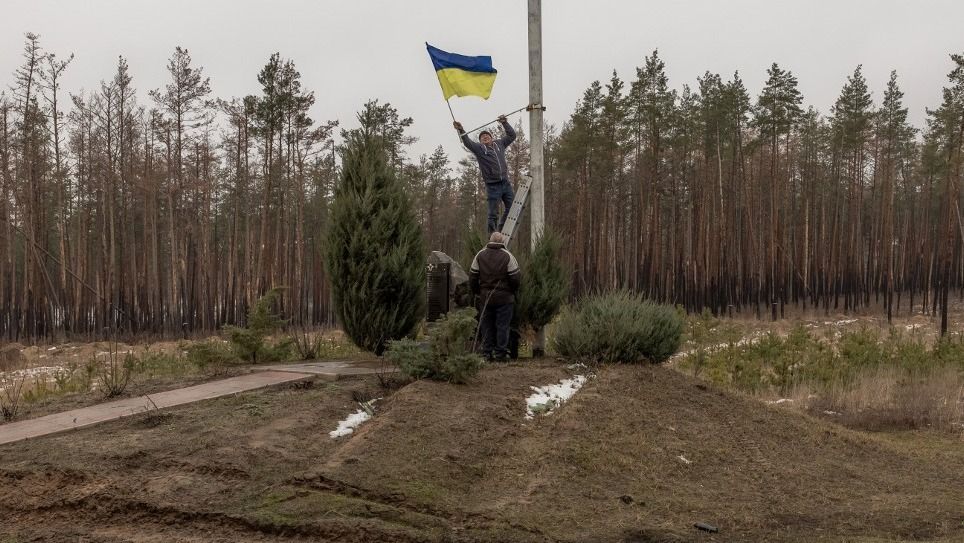 A man installs a Ukrainian flag on a memorial for Ukrainian soldiers in Kramatorsk district, on January 19, 2024, amid the Russian invasion of Ukraine. (Photo by Roman PILIPEY / AFP)