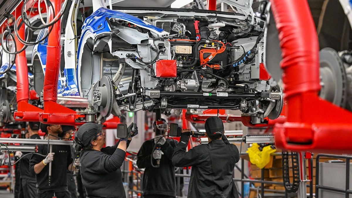 One year Tesla Gigafactory Berlin Brandenburg
20 March 2023, Brandenburg, Grünheide: Employees of the Tesla Gigafactory Berlin Brandenburg work on a production line of a Model Y electric vehicle. The Tesla plant was opened and put into operation on March 22, 2022. In the meantime, about 10,000 people are employed there. (to dpa "One year of Tesla plant in Germany - showcase factory and object of dispute") Photo: Patrick Pleul/dpa (Photo by PATRICK PLEUL / DPA / dpa Picture-Alliance via AFP) eurózónában