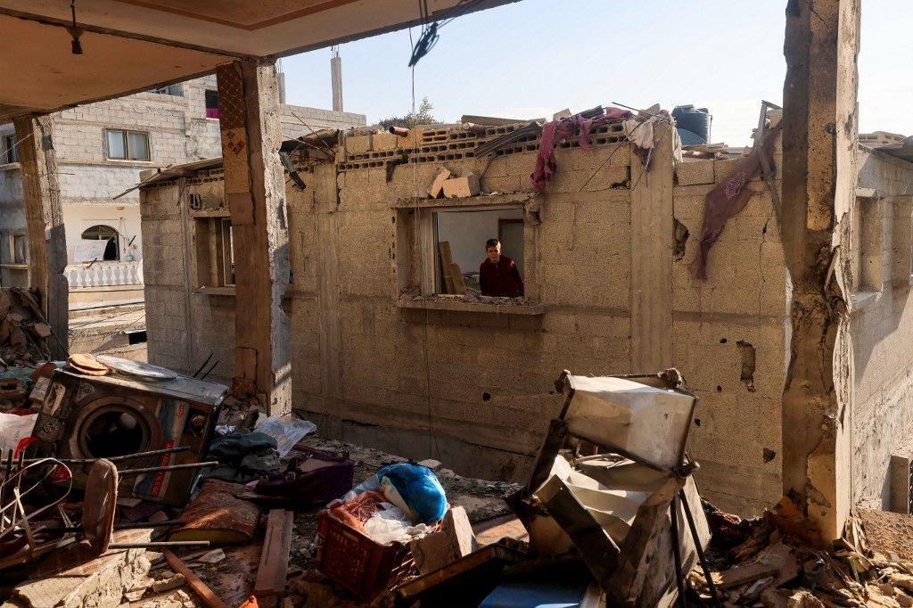 A child looks through the window of a destroyed house on January 5, 2024, following Israeli bombardment in Rafah, on the southern Gaza Strip, amid continuing battles between Israel and the Palestinian militant group Hamas. (Photo by AFP)