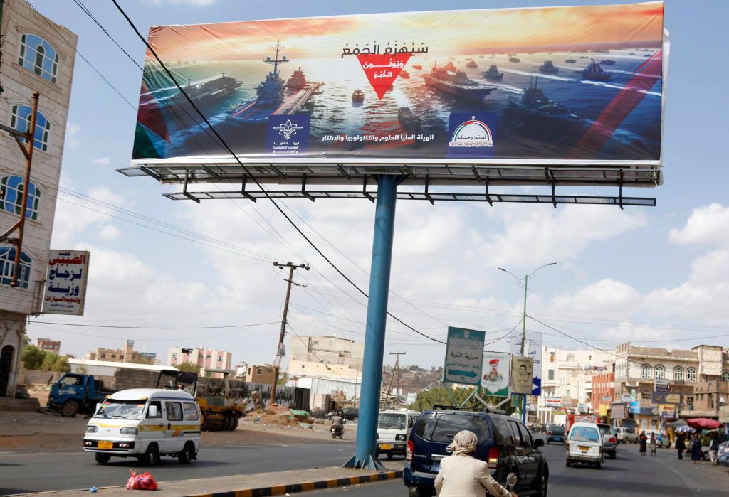 Yemen's Houthi In Frist Clashes With US Navy
,SANA'A, YEMEN - DECEMBER 31: Yemenis drive past a large billboard with a picture depicting the navy destroyers of foreign countries including the US and UK, and the words 'Navy coalition will be defeated' at a street on December 31, 2023 in Sana'a, Yemen. In the first direct clashes between the US Navy and Yemen's Houthis, American Navy helicopters stuck three navy boats of the Houthi forces in the Red Sea on Sunday morning, leading to the sunk of the boats and killing those aboard. (Photo by Mohammed Hamoud/Getty Images)