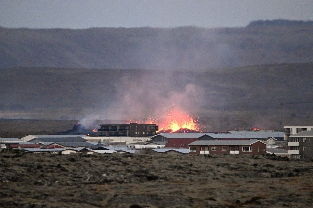 Lava explosions and billowing smoke are seen near residential buildings in the southwestern Icelandic town of Grindavik after a volcanic eruption on January 14, 2024. Seismic activity had intensified overnight and residents of Grindavik were evacuated, Icelandic public broadcaster RUV reported. This is Iceland's fifth volcanic eruption in two years, the previous one occurring on December 18, 2023 in the same region southwest of the capital Reykjavik. Iceland is home to 33 active volcano systems, the highest number in Europe. (Photo by Halldor KOLBEINS / AFP)