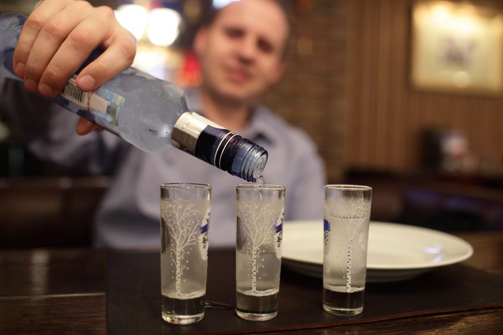 Man,Pouring,Vodka,Into,The,Glasses,At,The,Pub