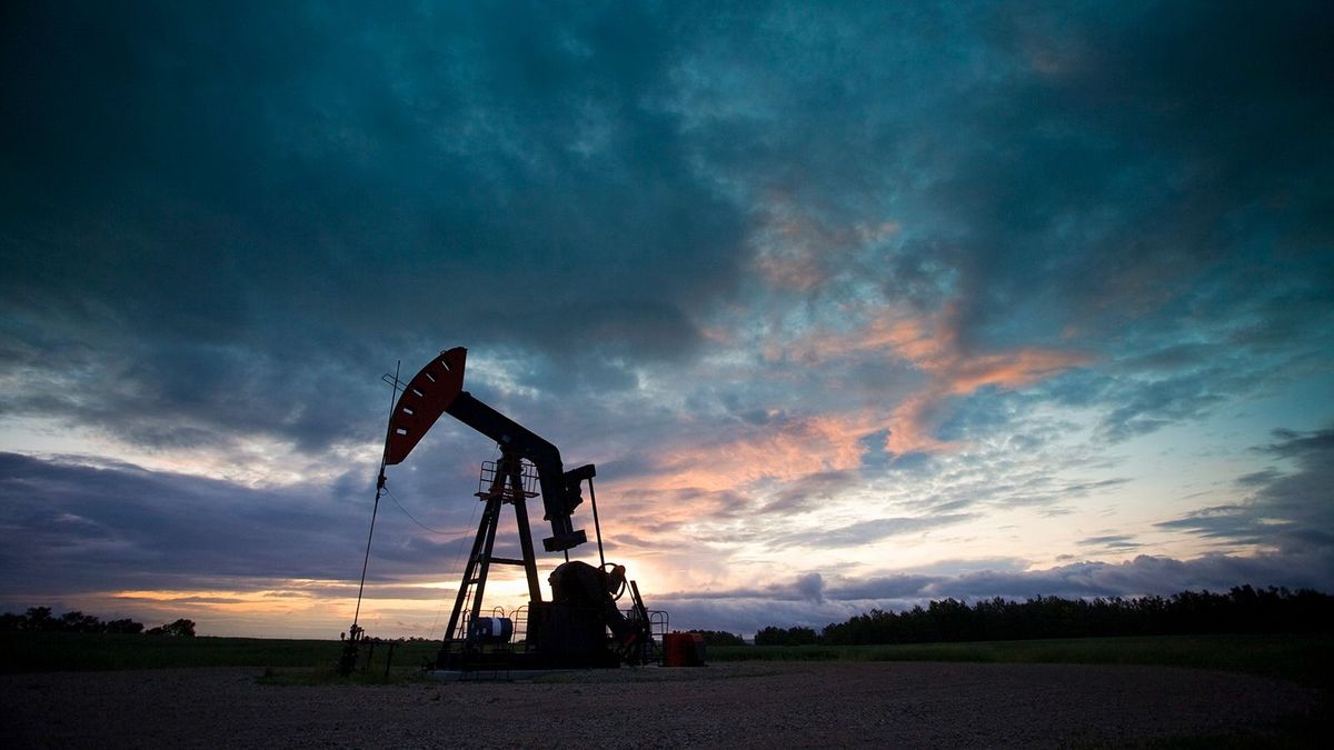 An oil derrick, a well head pump arm with frame, silhouetted against the evening sky. Oil business. 