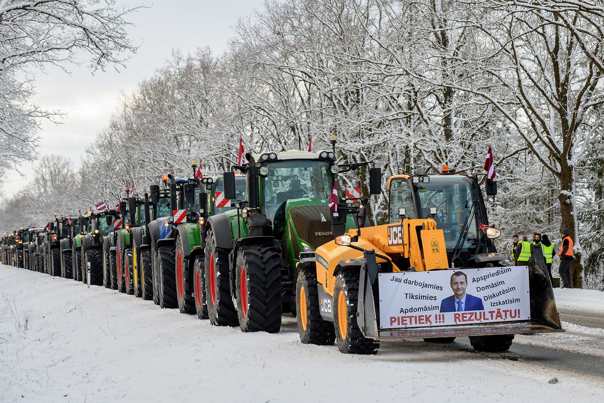 This photo taken on February 5, 2024 on a highway in Eleja, Latvia, near the border to Lithuania, shows a demonstration of farmers with their tractors as a placard is seen at the front of a tractor reading 'Stop! We need results!' and showing Latvian Agriculture Minister Armands Krauze. Latvian farmers hope to draw attention to problems in the agricultural sector and demand an immediate ban on imports of Russian and Belarusian food products. (Photo by Gints Ivuskans / AFP)