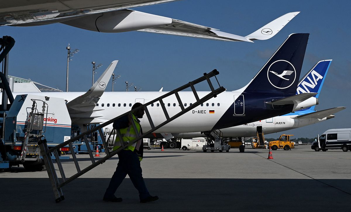 (FILES) An employee carries a ladder under an Airbus A 350 at the Lufthansa terminal of the Franz-Josef-Strauss-airport in Munich, southern Germany, on September 15, 2023. Ground staff at German airline Lufthansa will go on strike on February 7, 2024 in the latest industrial action to hit Europe's biggest economy, the Verdi union said. Some 25,000 staff will take part in the walkout, which will last for around 27 hours from 4:00 am (0300 GMT), the union said in a statement on February 5. The workers are demanding a 12.5-percent pay increase over 12 months as well as one-off bonuses to counter inflation, it said. (Photo by Christof STACHE / AFP)