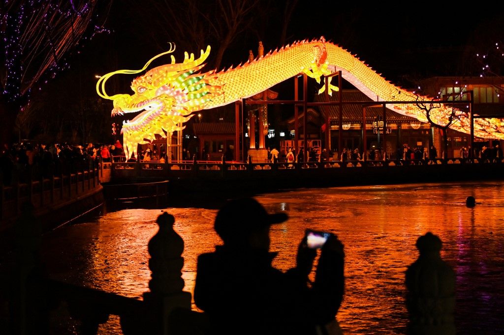 A man take photos of a giant dragon figure at a park in Beijing on February 9, 2024, which marks the eve of the Lunar New Year of the Dragon. (Photo by GREG BAKER / AFP)