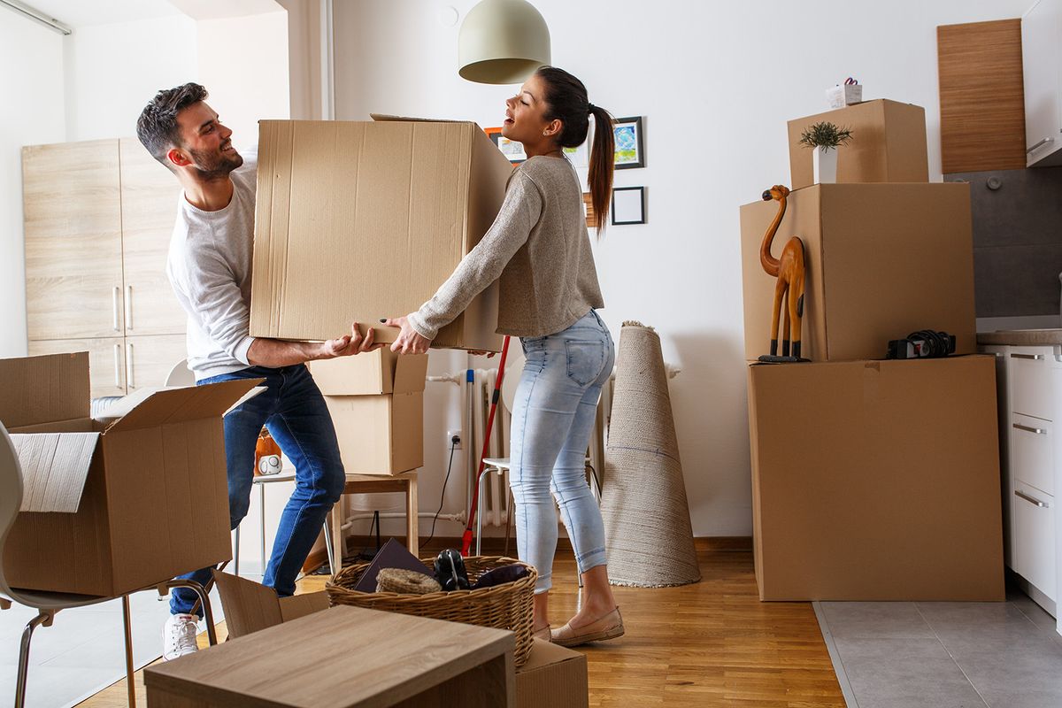 Young,Couple,Carrying,Big,Cardboard,Box,At,New,Home.moving,House.