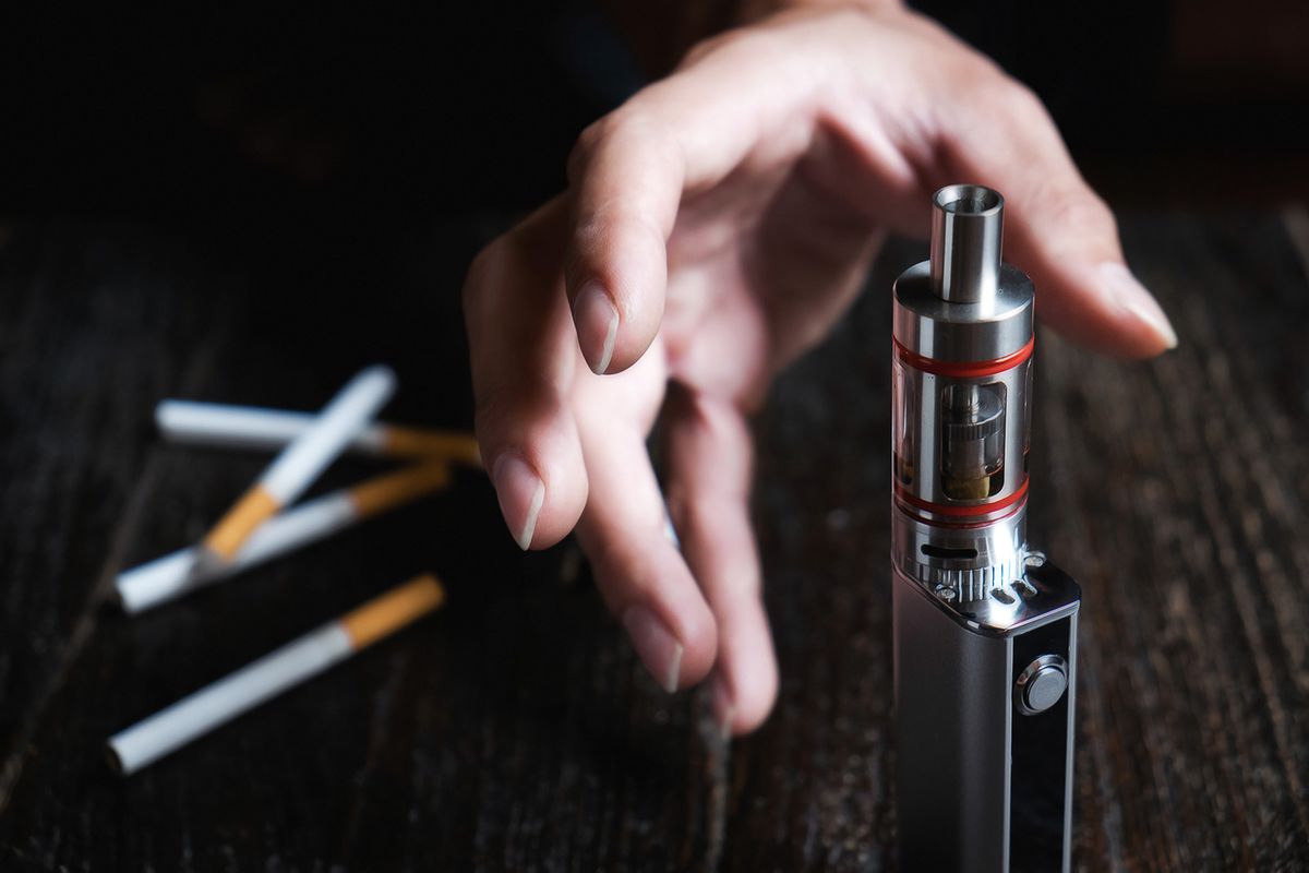 Close up of man hand holding electronic cigarette try to stop smoking cigarette. Concept of tobacco day.