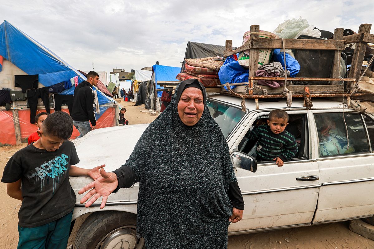 A woman reacts as she stands before a vehicle loaded with items secured by rope as people flee from Rafah in the southern Gaza Strip on February 13, 2024 north towards the centre of the Palestinian territory amid the ongoing conflict between Israel and the Palestinian militant group Hamas. (Photo by MOHAMMED ABED / AFP)