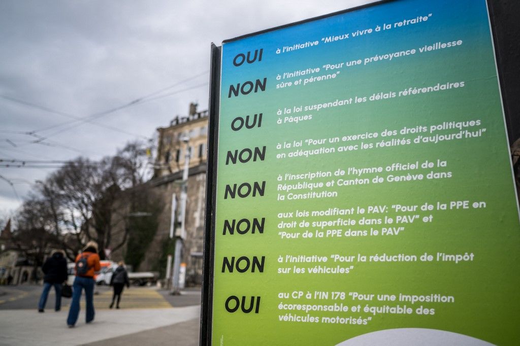 Pedestrains walk past a referendum poster, ahead of two referendum on retirement initiatives, including on the raise of the retirement age, in Geneva, on February 27, 2024. The Swiss will vote on March 3, 2024 on two initiatives aimed at reshaping life for pensioners in diametrically different ways, with one calling to boost pension payments and the other to hike the retirement age. (Photo by Fabrice COFFRINI / AFP)