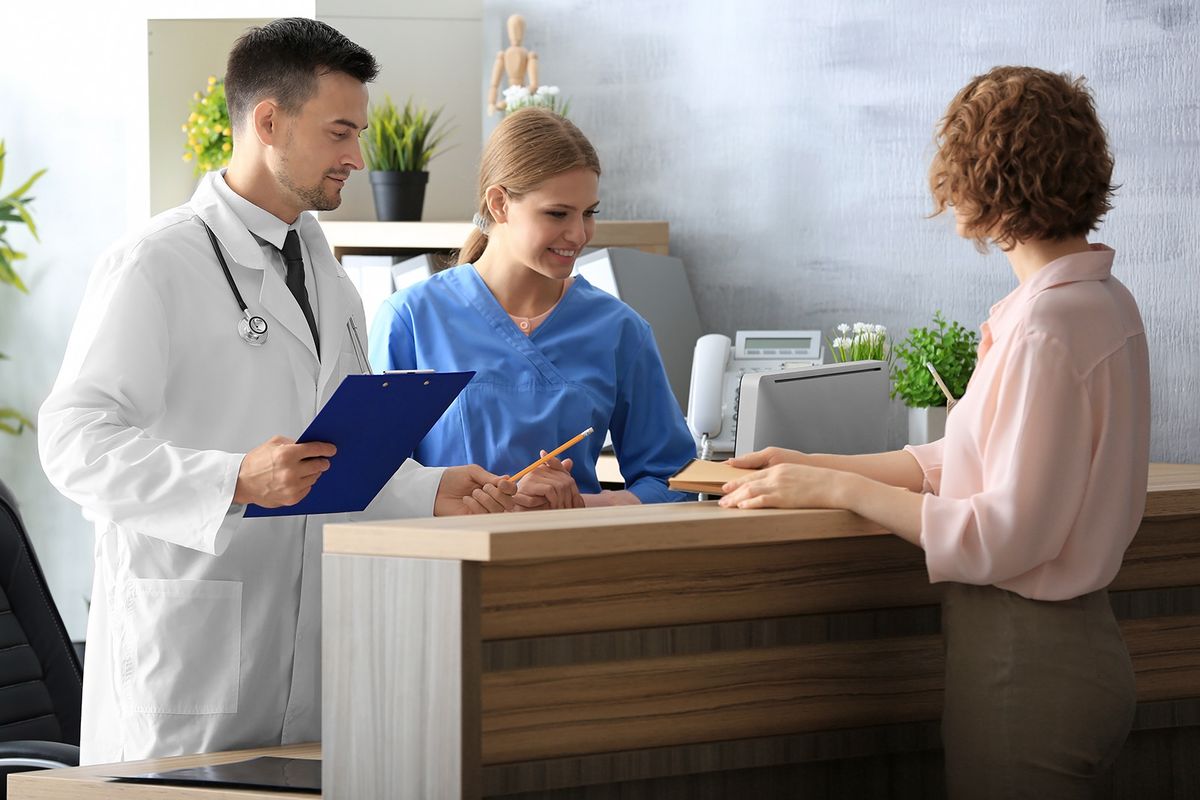 Receptionist,And,Doctor,With,Client,In,Hospital