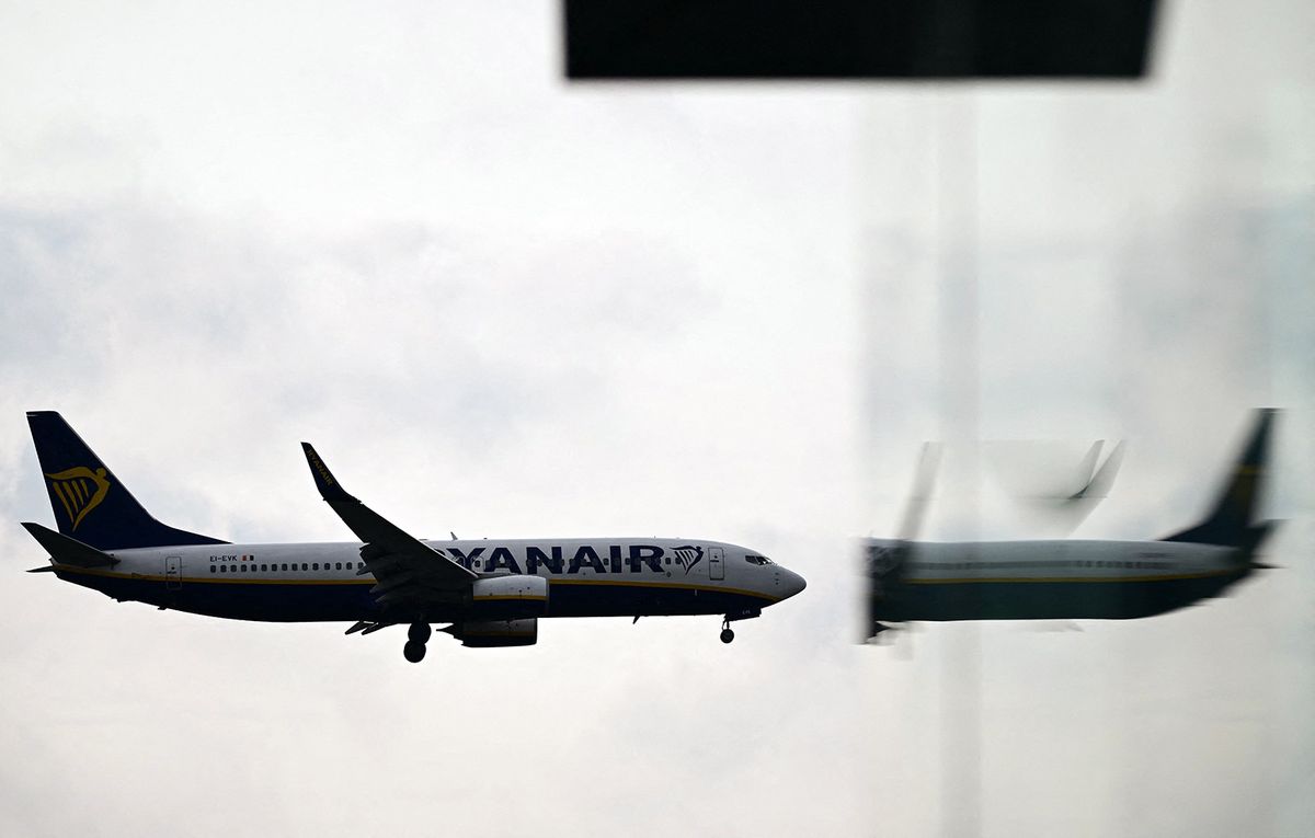 (FILES) A Ryanair Boeing 737-8AS aircraft is reflected in a window as it prepares to land at London Gatwick Airport, near Crawley, southern England, on September 26, 2023. Irish low-cost airline Ryanair saw its profit plunge in the third quarter of 2023/2024 due to soaring costs, and has cut its forecast for the year. Group share of net profit fell 93% to €14.8 million, despite a 17% increase in turnover to €2.7 billion. (Photo by Ben Stansall / AFP)