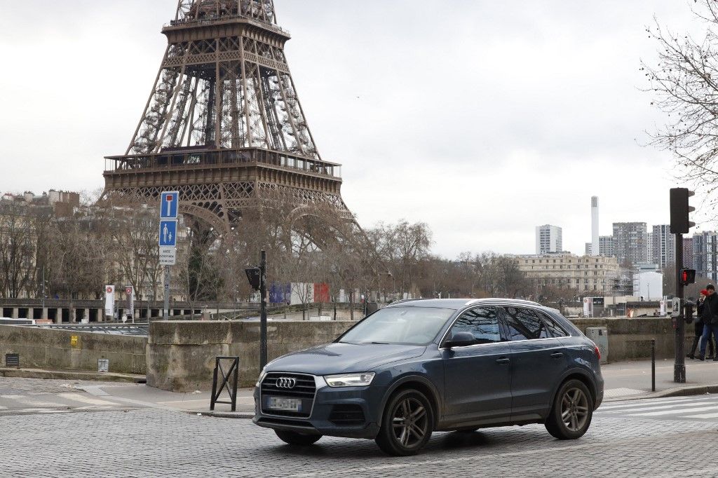 A local resident drives his sport utility vehicle (SUV) in the center of Paris, with the Eiffel Tower seen in the background, on January 30, 2024. On February 4, 2024 Paris' city hall is organizing a vote on the status of the heaviest and most polluting SUVs, and the creation of a special parking fee for these vehicles. (Photo by Nancy Wangue MOUSSISSA / AFP)