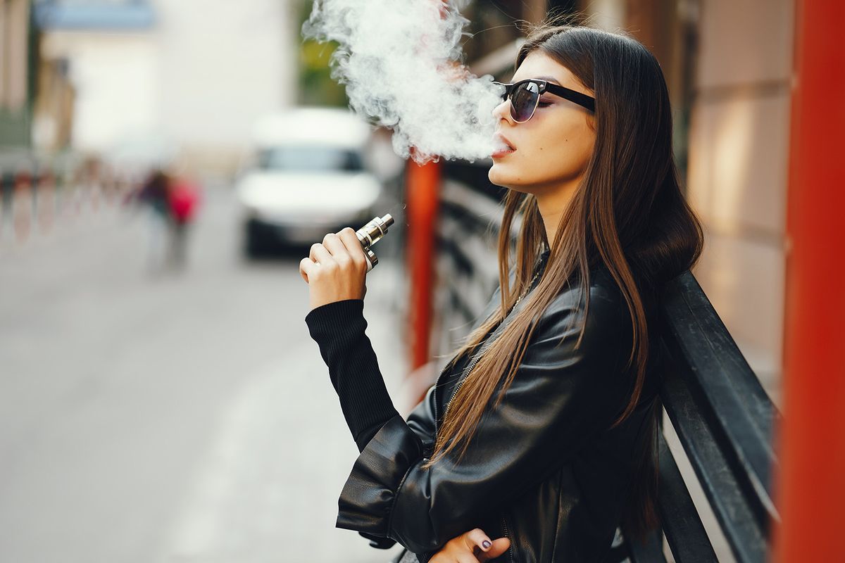 Stylish,Girl,Smoking,An,E-cigarette,As,She,Is,Walking,Through