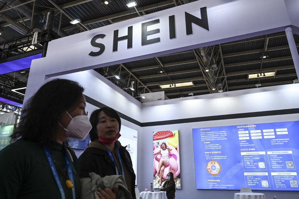 People walk past the booth of fast fashion e-commerce company SHEIN during the China International Supply Chain Expo (CISCE) in Beijing on December 1, 2023. (Photo by JADE GAO / AFP)