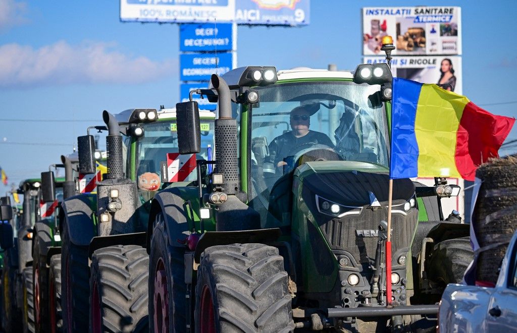 Románia megegyezett a gazdákkal és a fuvarozókkal.
ROMANIA-FARMERS-TRANSPORTERS-PROTESTRomanian farmers slowly drive their tractors on the road to Bucharest in Afumati village during protests on January 16, 2024. All over Romania around 4,500 truck drivers and farmers slowed traffic around several cities, including the capital Bucharest, voicing a string of grievances from high tax rates to slow compensation payouts. Past days, protesters also gathered at border areas, temporarily blocking the northeastern border with Ukraine. The truck drivers are complaining over high insurance and tax rates and long waiting times at the borders. At the same time, the farmers are seeking speedier payment of subsidies and compensation for those affected by drought or by disruptions caused by the import of Ukrainian cereals. (Photo by Daniel MIHAILESCU / AFP)