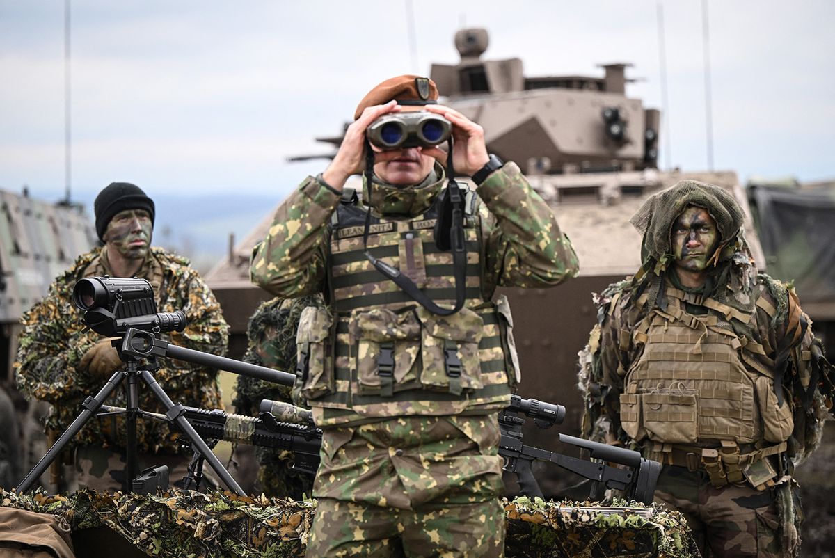 A Romanian army officer (C) tests binoculars next to soldiers from a special troop of the French army during a military exercise on November 25, 2022 in Cincu, Romania. Approximately 600 servicemen from Romania, France, Poland, Portugal and the US, with over 70 technical means, take part in the joint training exercise "BLACK SCORPIONS 22.8", at the National Joint Training Center (CNIÎ) "Getica" in the town of Cincu, Bra?ov county. (Photo by Daniel MIHAILESCU / AFP)