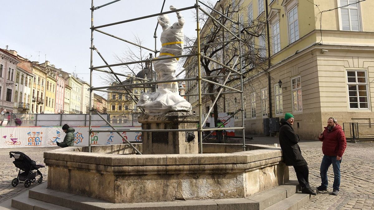 People stand near the wrapped statue of Diana, sitting atop a fountain, near the city council in Lviv, western Ukraine, on March 12, 2022.
